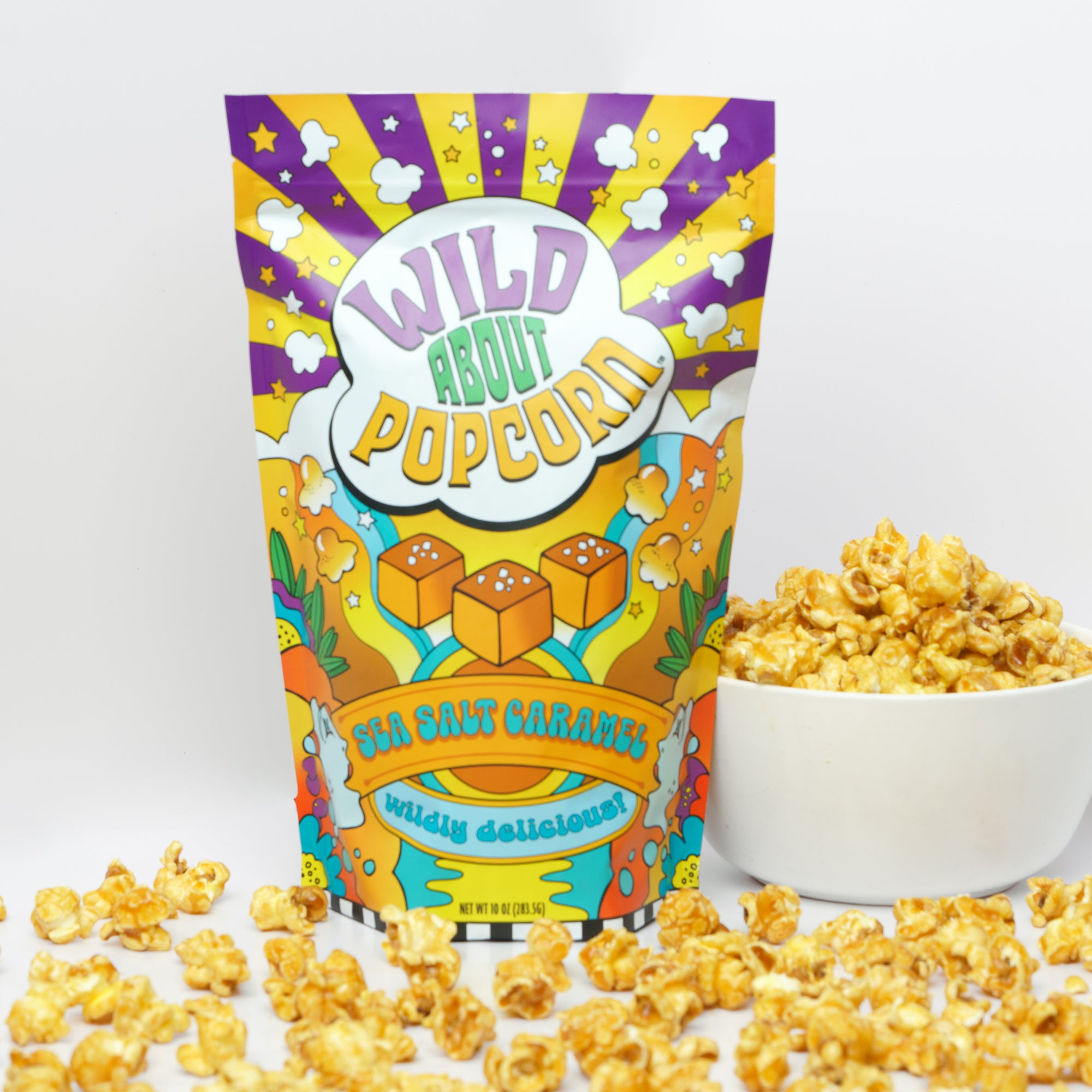 A colorful bag of Wild About Popcorn with a graphic of popcorn and a sprinkle of sea salt on top. The bag is placed in front of a bowl of popped popcorn.